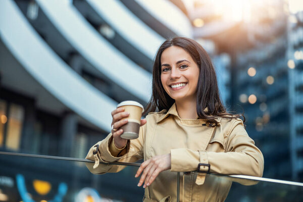 Business woman using smart phone and drinking coffee to go before going to work early in the morning.