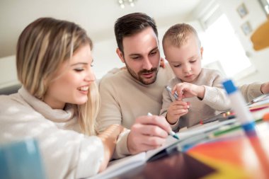 Anne ve baba evde çocuklarıyla birlikte resim çiziyorlar..