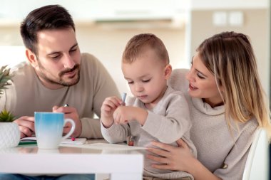 Anne ve baba evde çocuklarıyla birlikte resim çiziyorlar..