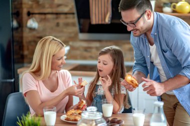 Genç aile kahvaltısını evde yapar. Mutfakta kurabiye yiyip süt içiyorlar. Aile, aşk ve yaşam tarzı konsepti..