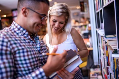 Kütüphanedeki üniversite öğrencileri projeleri için yeni bilgiler arıyorlar.