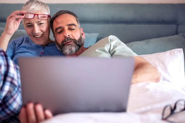 Uśmiechnięta Para Seniorów Siedząca Łóżku Laptopem Dzwoniąca Wideo — Zdjęcie stockowe