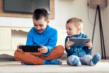 Evdeki tablette video oyunu oynayan çocuklar.
