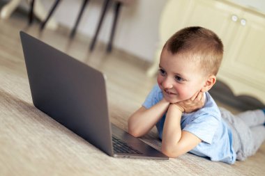 Dizüstü bilgisayarı olan küçük çocuk evde çizgi film izliyor..