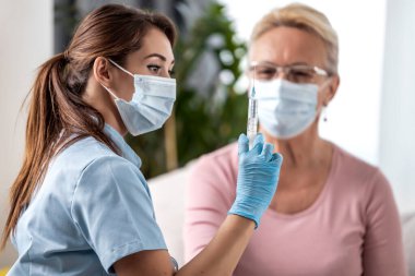 Doktor yaşlı bir kadına aşı yapıyor. Virüs koruması. COVID-2019. İlaç ve sağlık hizmetleri kavramı.