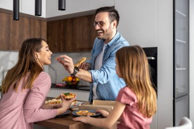 Anne, baba ve kızı mutfakta birlikte yemek yiyorlar. Mutlu aile kavramı..