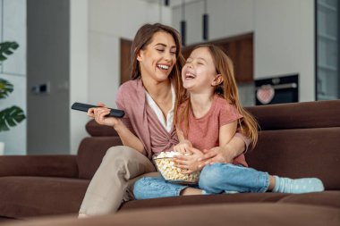 Hafta sonu evde. Annesiyle televizyon izleyen, patlamış mısır yiyen tatlı küçük bir kız..