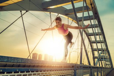 Şehirdeki fitness antrenmanından önce genç bir kadın antrenman yapıyor. Dışarıda ısınıyor..