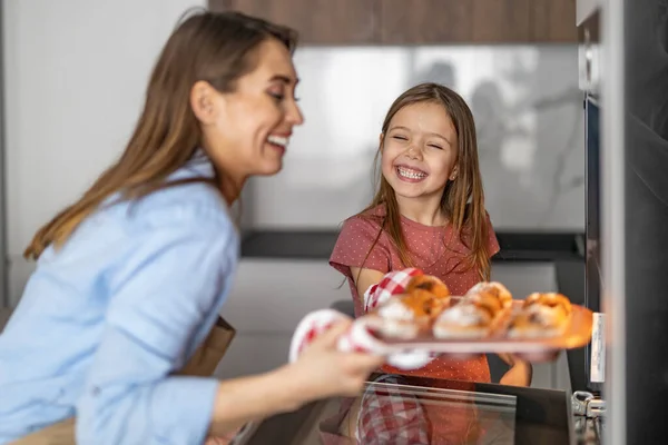 魅力的な母親と彼女のかわいい娘は台所で一緒にマフィンを作っています 彼らは一緒に過ごす時間を楽しんでいる — ストック写真