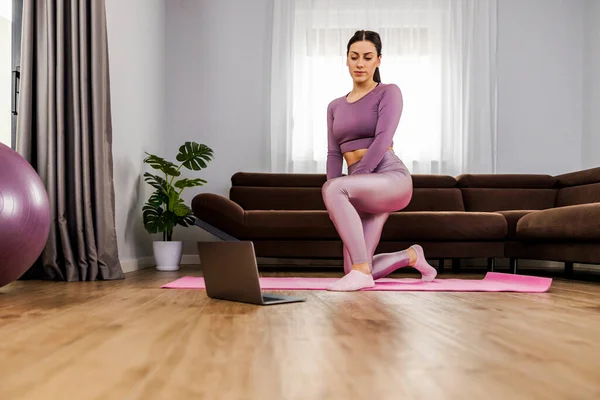 穿着运动服的健康女性在家里的笔记本电脑前锻炼 观看健身录像 人和生活方式的概念 — 图库照片