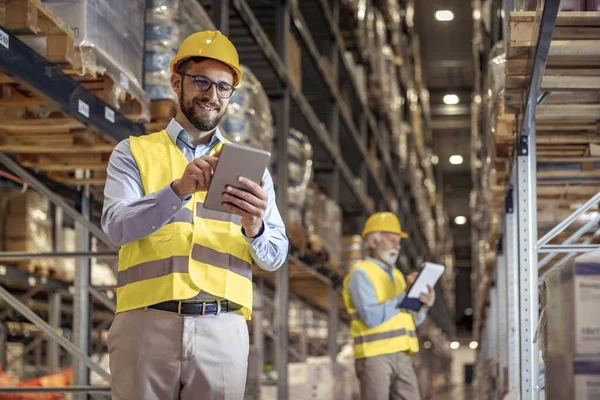 Stock image Young man working in warehouse and looking at tablet.