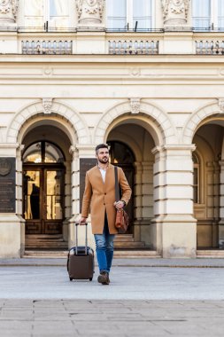 Bavullu genç bir işadamı şehirde yürüyor. İş seyahati..