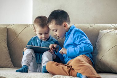 Evdeki tablette video oyunu oynayan çocuklar.