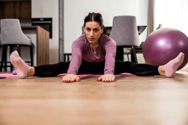 Oturma odasında egzersiz yapan genç bir kadın. Video dersi. 