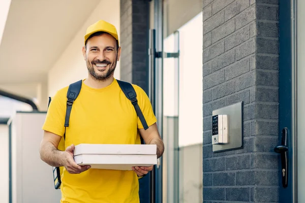 Photo of man from delivery service in yellow t-shirt holding two pizza boxes. Fast delivery service concept.