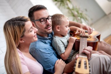 Mutlu aile evde birlikte eğleniyor, gitar çalıyor..