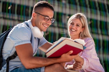 Açık havada kitap okuyan çiftlerin portresi, bankta oturup birlikte öğreniyorlar..