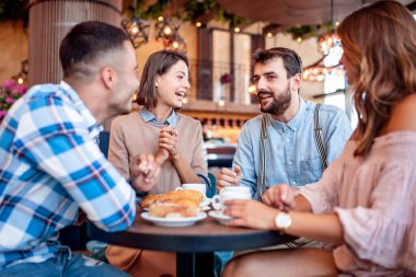 Bir grup mutlu arkadaş restoranda kahvaltı edip kahve içiyorlar. İnsanlar, eğlence, arkadaşlık ve mutluluk kavramı.