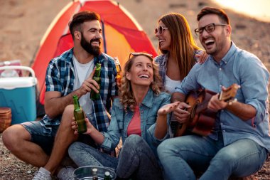 Bir grup heyecanlı genç arkadaş sahilde birlikte eğleniyor, bira içiyor..