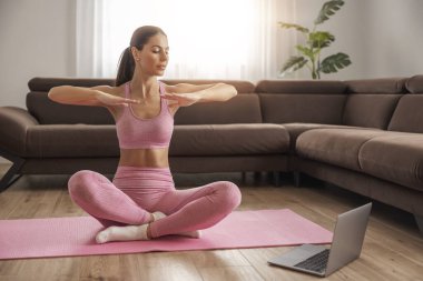 Evde esneme hareketleri yapan çekici genç bir kadın. Sağlıklı yaşam tarzı konsepti..