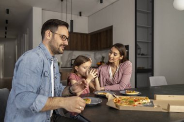 Anne, baba ve kızı mutfakta birlikte yiyorlar. Mutlu aile kavramı.