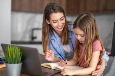 Anne ve kızı evde birlikte ev ödevi yapıyorlar..