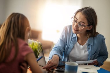 Anne ve kızı evde birlikte ev ödevi yapıyorlar..