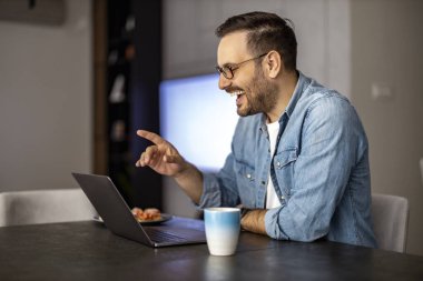 Dizüstü bilgisayar kullanan, e-posta yazan, online görüşme ya da internet üzerinden ödeme yapan bir adam. Ev ofisinden çalışan serbest çalışan biri..