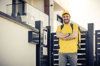 Yemek teslimatı yapan kurye üniformalı genç bir adam. Kameraya bakıyor..