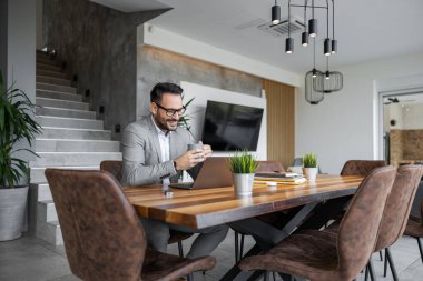 Genç işadamı bilgisayarında çalışıyor. İş adamı müşterisiyle görüntülü görüşme yapıyor..