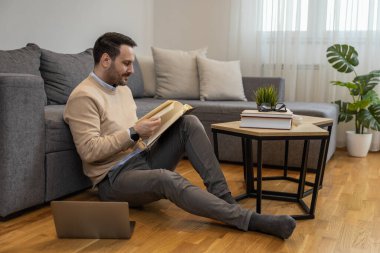 Genç adam internette elektronik öğrenim ya da fatura ödemek için dizüstü bilgisayar kullanıyor. İş, insan ve teknoloji kavramı.