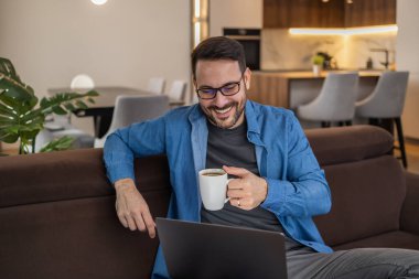 Dizüstü bilgisayar kullanan, e-posta yazan, online görüşme ya da internet üzerinden ödeme yapan bir adam. Ev ofisinden çalışan serbest çalışan biri..