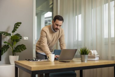 Genç adam internette elektronik öğrenim ya da fatura ödemek için dizüstü bilgisayar kullanıyor. İş, insan ve teknoloji kavramı.