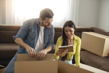 Mutlu genç çift yeni bir daireye taşınıyor ve kutuları açıyor. Birlikte mutlu anlar..