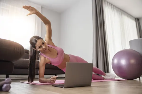 Fitness woman doing plank exercise in living room. Attractive girl exercising at home.Online training.