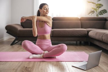 Evde esneme hareketleri yapan çekici genç bir kadın. Evde online eğitim. Formda kal.