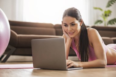 Evde egzersiz yapan çekici genç bir kadın. Evde online eğitim. Formda kal.