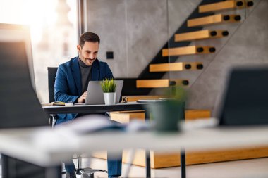 Modern ofisteki masasında çalışan bir iş adamı. Genç, endişeli, takım elbiseli, dizüstü bilgisayarla çalışan bir girişimci..