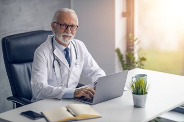 Çevrimiçi doktor randevusu. Online danışmanlık yapan kıdemli erkek doktor. Kameraya bakıyor..