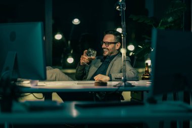 Gecenin geç saatlerinde bilgisayarda çalışan yakışıklı iş adamının portresi. İşadamı gece geç saatlere kadar bilgisayarla ofiste çalışıyor..