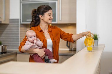 Genç anne mutfakta sağlıklı portakal suyu içiyor. Sağlıklı yaşam tarzı kavramı.