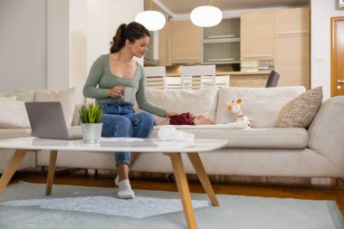 Mutlu anne bebeğiyle birlikte evde çalışıyor. İş, annelik, çoklu görev ve aile kavramı..