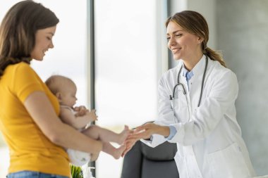 Anne ve şirin bebeği klinikte çocuk doktorunu ziyaret ediyor. Bebek doktoru ve doktor ofisinde bebeği var..