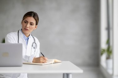 Kadın doktor portresi klinikte online bir hastayla konuşuyor. Yurtiçi sağlık tedavisi için online danışmanlık yapıyor. O, yoğun bir iş gününden sonra baş ağrısı çekiyor..