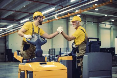 İş yerinde elektrikli forklift kullanan işçiler. Ticarette siparişleri taşıma ve işleme.