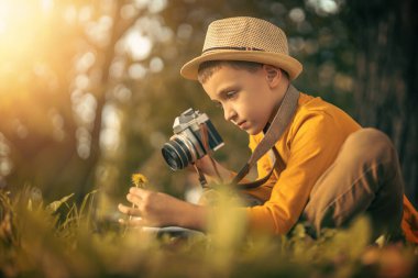 Küçük beyaz bir çocuğun sonbahar portresi. Küçük çocuk fotoğraf çekiyor, klasik film kamerası kullanıyor..