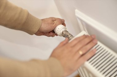 Soğuk kış günlerinde ellerini radyatörde ısıtan bir adam. Ev merkezi ısıtma sistemi..