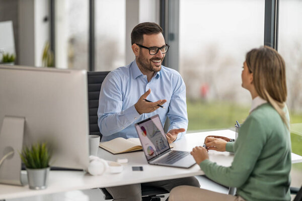 Creative people meeting in an office using computer and talking about new plans.Web designers working at office and planning new website.