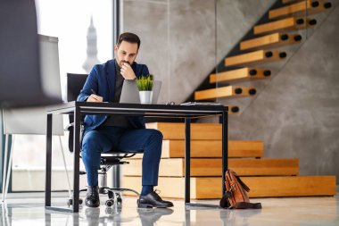 Modern ofisindeki iş yerindeki başarılı girişimcinin görüntüsü. Ciddi genç işadamı müşterisiyle görüntülü görüşme yapıyor..