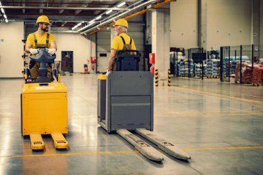 İş yerinde elektrikli forklift kullanan işçiler. Ticarette siparişleri taşıma ve işleme.